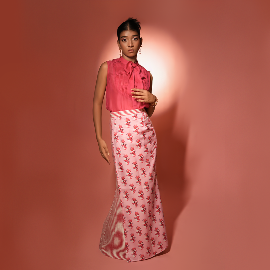 Woman wearing a pink sleeveless top and Pink  Dragon flap skirt against a 